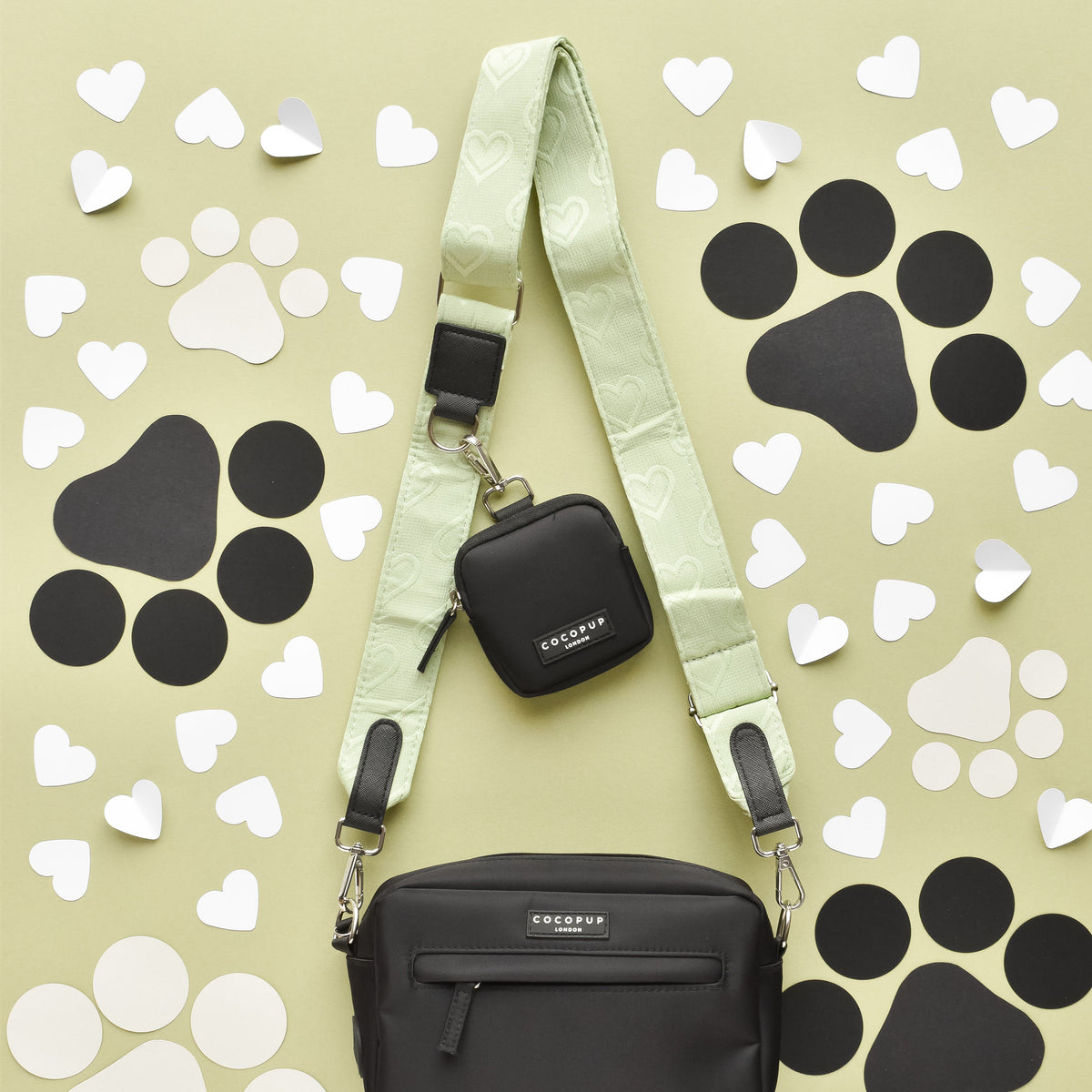 Black Cocopup London dog walking bag with mint strap, paper heart accents, and attached poop bag dispenser.