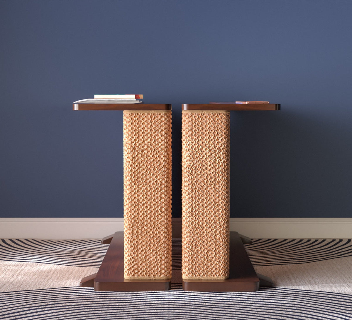A Cat-e-Corner table placed next to a sofa, integrating a cat's scratching post with a small table, in a room with a plant and a colorful cushion.