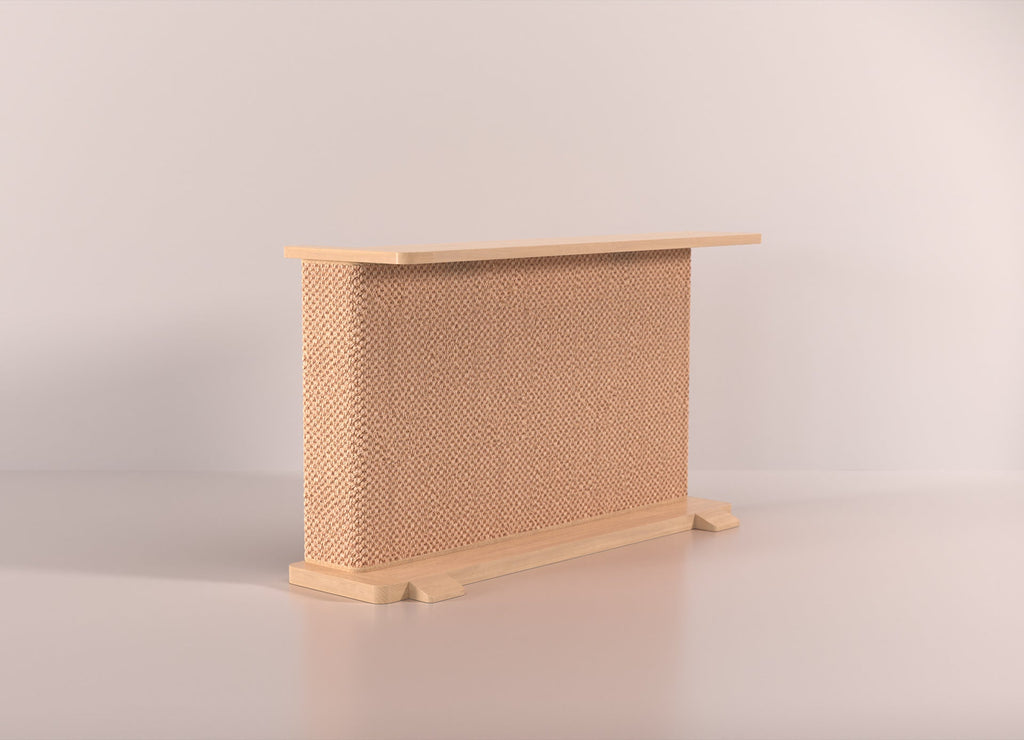 A Cat-e-Corner table placed next to a sofa, integrating a cat's scratching post with a small table, in a room with a plant and a colorful cushion.